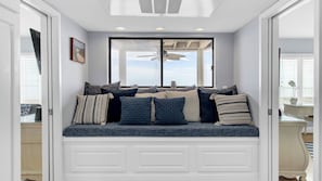 Ein Zimmer mit einer eingebauten Sitzbank, einem Deckenventilator und einem großen Fenster.