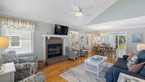 A living room with a fireplace, television, and dining area. - 55 Pelican Bay by Avantstay Easy Beach Access + Shared Pool + Screened Porch + Ping Pong (Isle of Palms)