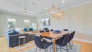 A modern living room with a sofa, chairs, a dining table, and a ceiling fan.