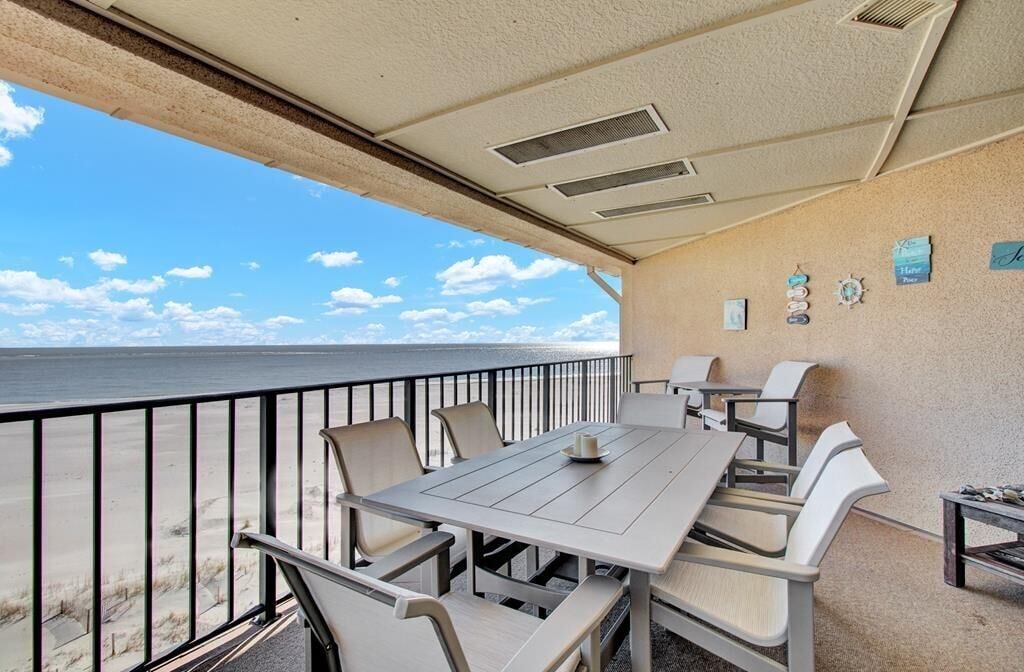 A covered outdoor seating area with a view of the beach and ocean.