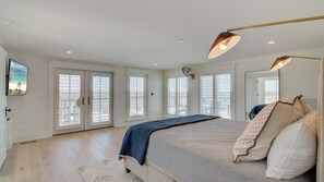 Un dormitorio con una cama grande, varias ventanas y un ventilador de techo.