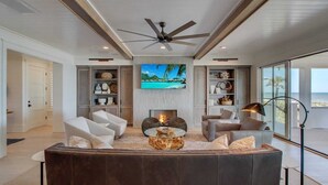 A modern living room with a fireplace, comfortable seating, and a large TV. - 710 Ocean Boulevard Avantstay Oceanfront, Private Pool + Rooftop Deck (Isle of Palms)
