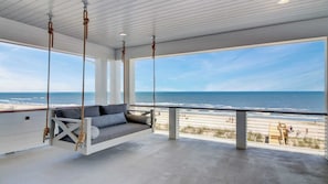 A spacious balcony with a swing chair overlooking a beach. - 710 Ocean Boulevard Avantstay Oceanfront, Private Pool + Rooftop Deck (Isle of Palms)
