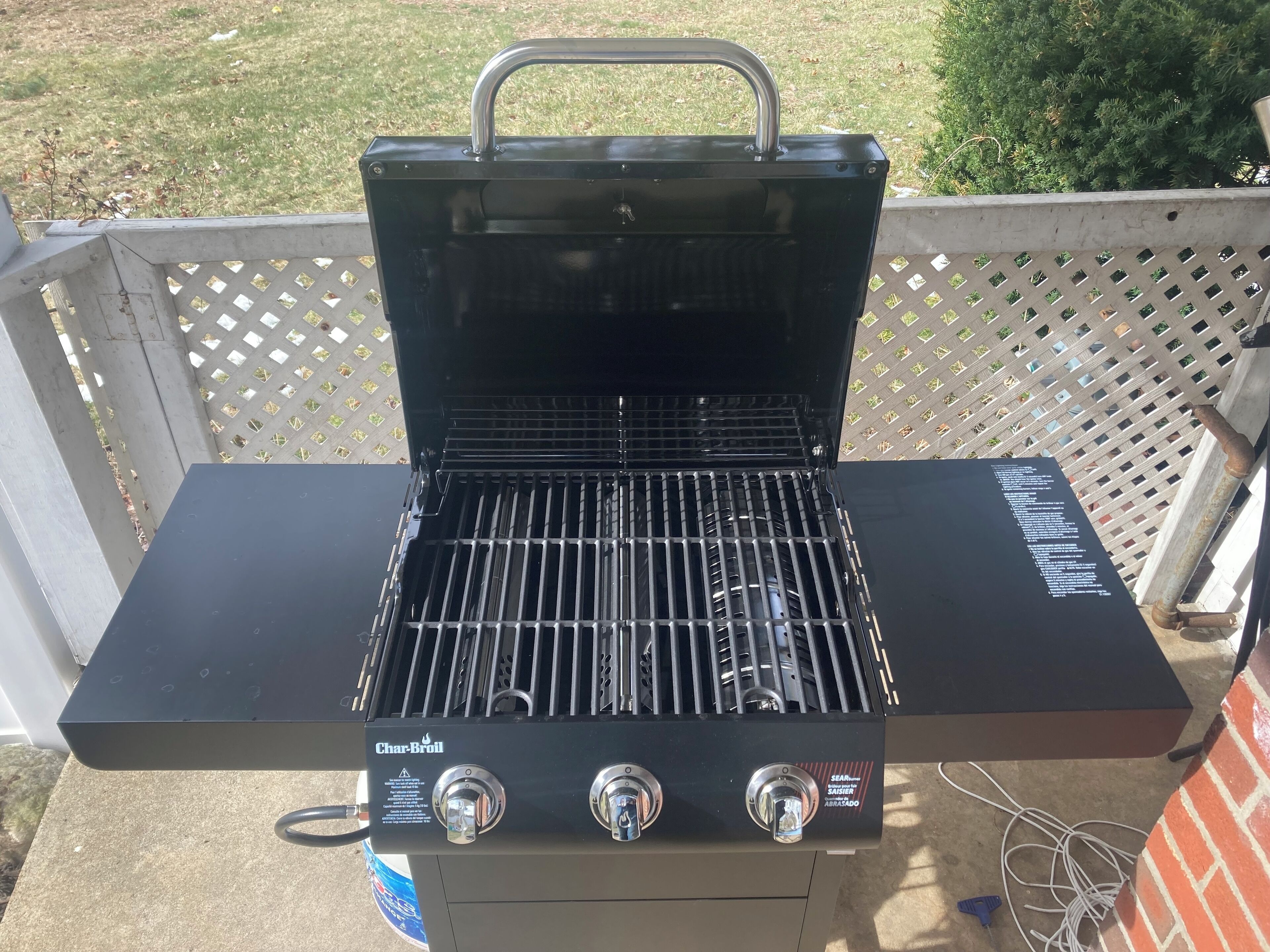 Una barbacoa Char-Broil amb tres comandaments i una nansa metàl·lica a la part superior.