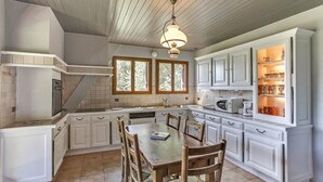 A kitchen with white cabinets, a wooden dining table, and a hanging light fixture.