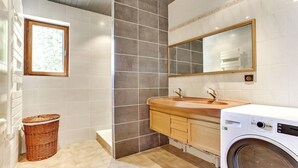 A modern bathroom with a large mirror, a sink, and a washing machine.