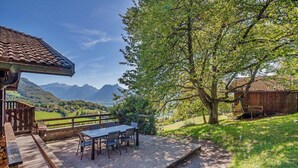 A terrace with a table and chairs, overlooking a mountainous landscape.
