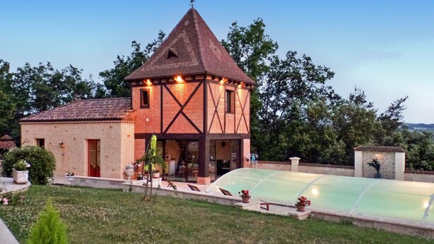 Une maison traditionnelle à colombages, dotée d’un toit à forte pente et d’une petite tour.
