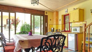 Un coin repas avec une table dressée pour quatre personnes, une cuisine avec des placards jaunes et une vue sur l’extérieur.