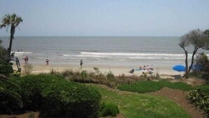 A beach with people walking and sitting under umbrellas. - 121 D Shipwatch by Avantstay Oceanfront Villa w/ View (Isle of Palms)