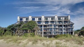 A multi-story hotel with balconies, located near a beach with sand and vegetation. - 121 D Shipwatch by Avantstay Oceanfront Villa w/ View (Isle of Palms)
