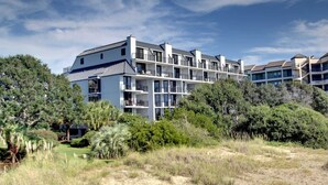 A multi-story residential building with balconies, surrounded by dense greenery and trees. - 121 D Shipwatch by Avantstay Oceanfront Villa w/ View (Isle of Palms)