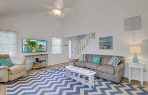 Relax in this stylish living room with a ceiling fan, flat-screen TV, and comfortable sofa.