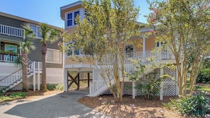 A residential building with a covered porch, a staircase, and a gated entrance.