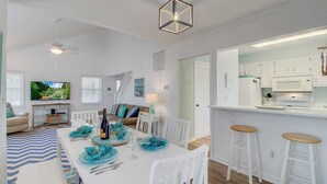 A modern kitchen with white cabinets, a central island, and bar stools.