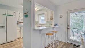 A modern kitchen with white cabinetry, a built-in oven, and a window overlooking a balcony.
