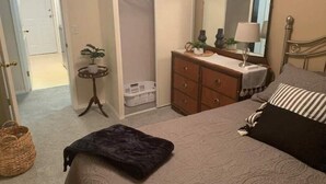 Un dormitorio con cama, cómoda, espejo y armario.