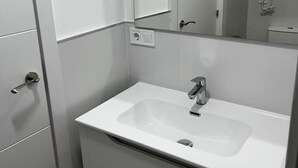 A modern bathroom with a white sink, mirror, and cabinet. - Studio Apartment universidad (Madrid)
