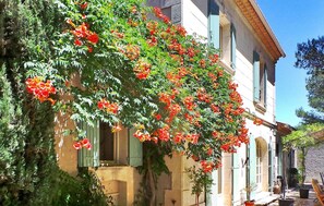 Un edificio con jardín que presenta flores rojas y follaje verde.