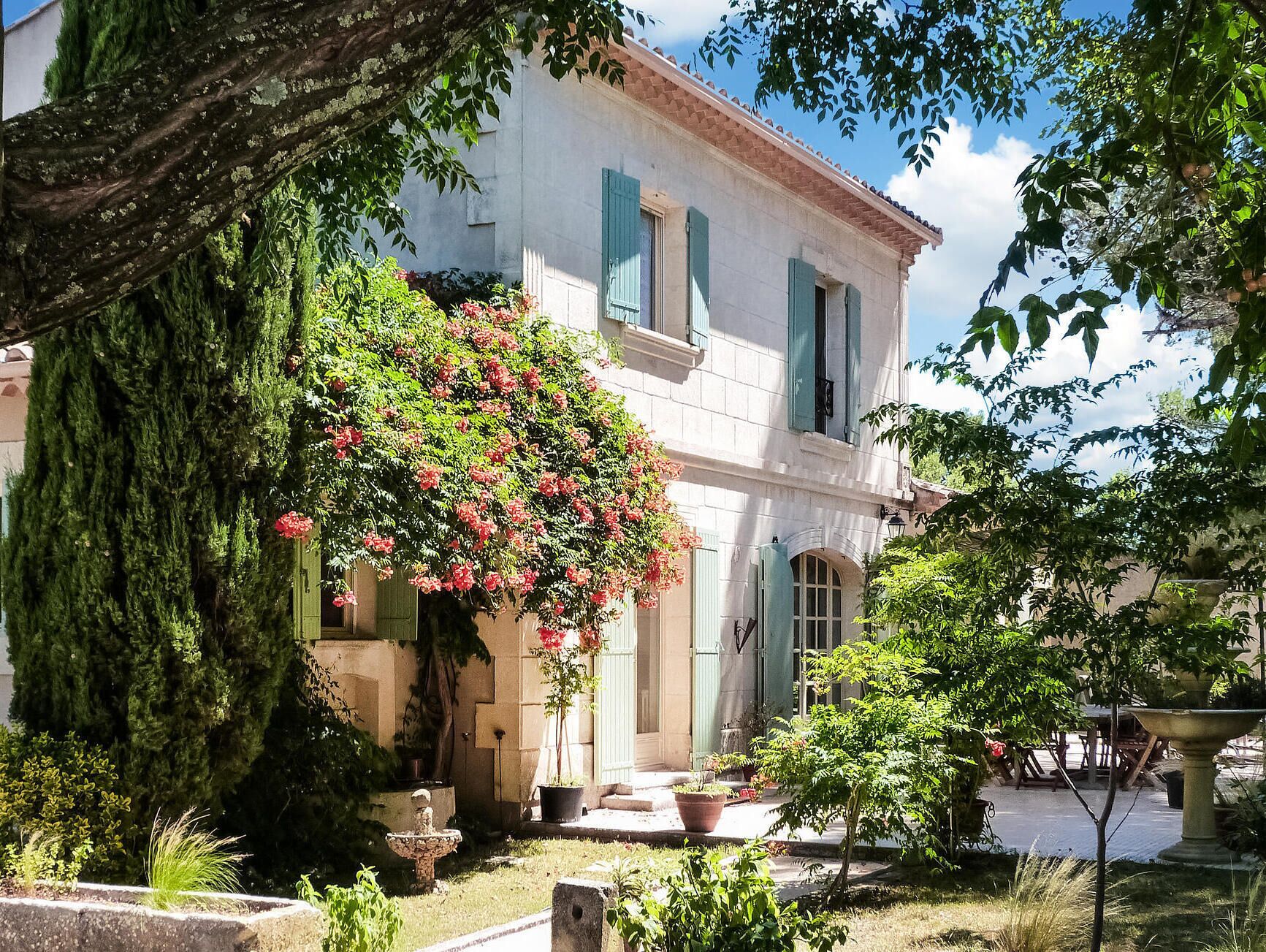 Un bâtiment traditionnel doté d’un jardin, d’une fontaine en pierre et de plantes en pot.