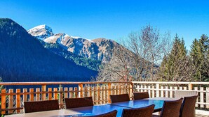 An outdoor dining area with a view of snow-capped mountains and trees.