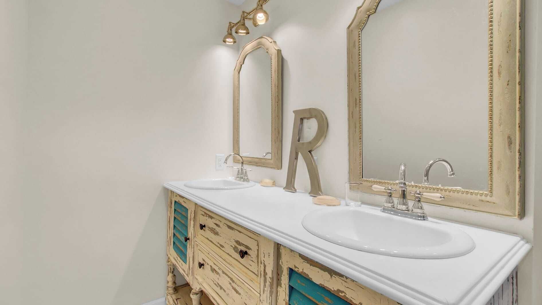 Une salle de bain avec deux lavabos, un grand miroir et une coiffeuse de style vintage.