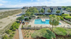 A beachfront hotel with a swimming pool, multiple balconies, and a beach view. - 304 E Port O Call by Avantstay Rooftop Deck Incredible Ocean & Beach Views! (Isle of Palms)