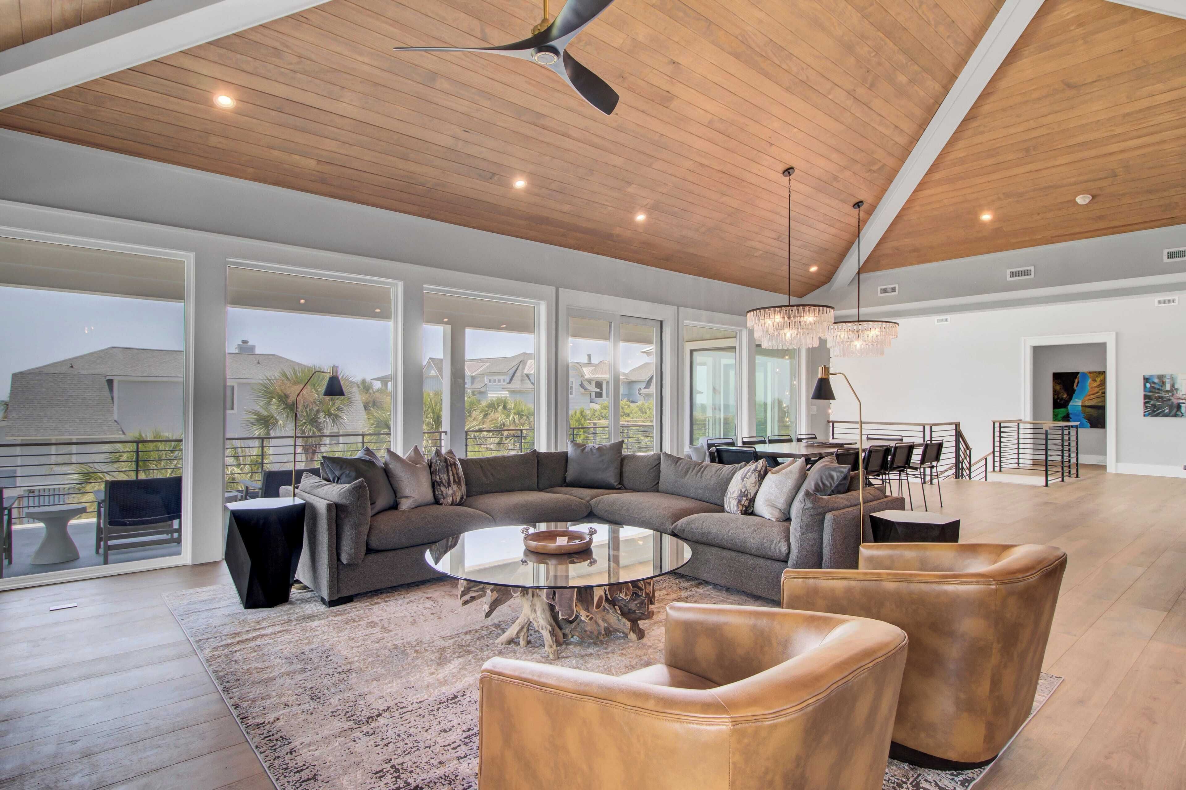 A spacious living area with a large sectional sofa, leather armchairs, and a round coffee table.