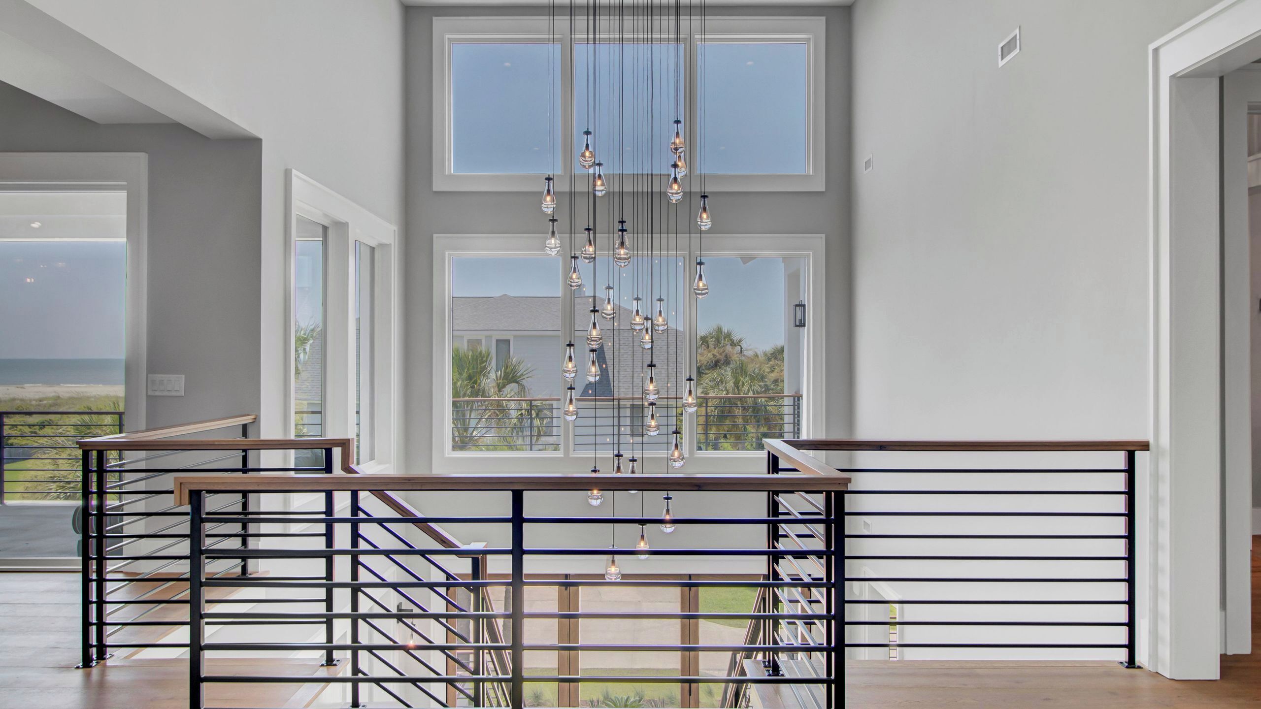 A spacious room with large windows, a staircase, and a hanging light fixture.