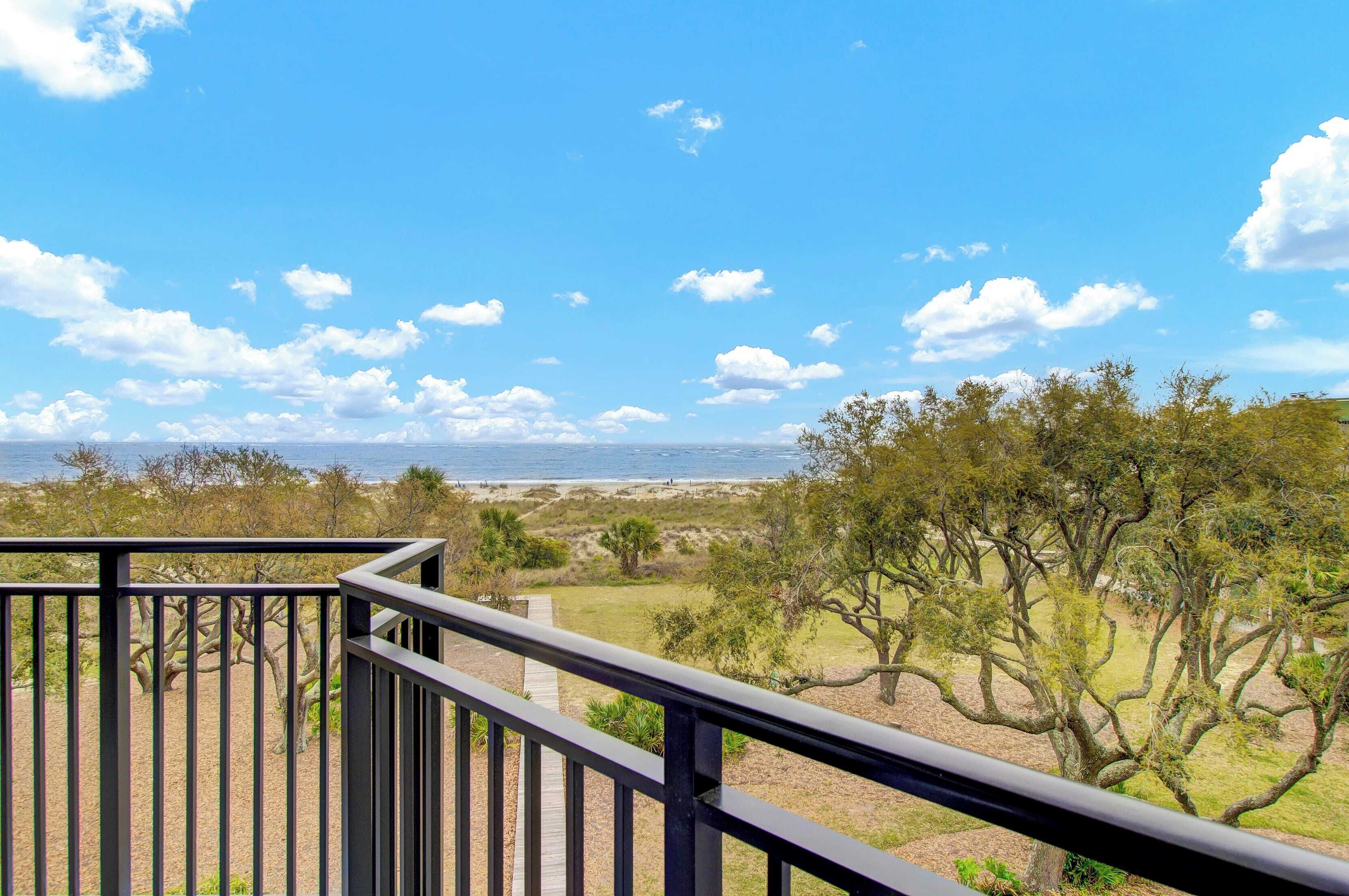 A balcony with a view of the beach and trees.