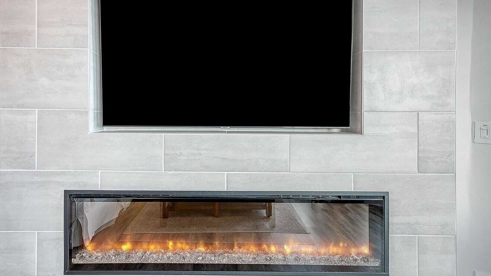 A fireplace with a TV above it, set in a room with light-colored tiled walls.