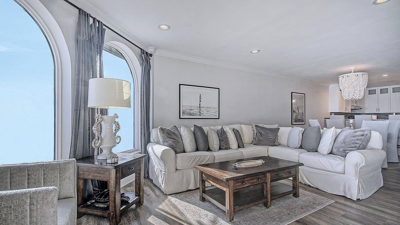 A modern living room with a large window, a sofa set, a coffee table, and a chandelier.
