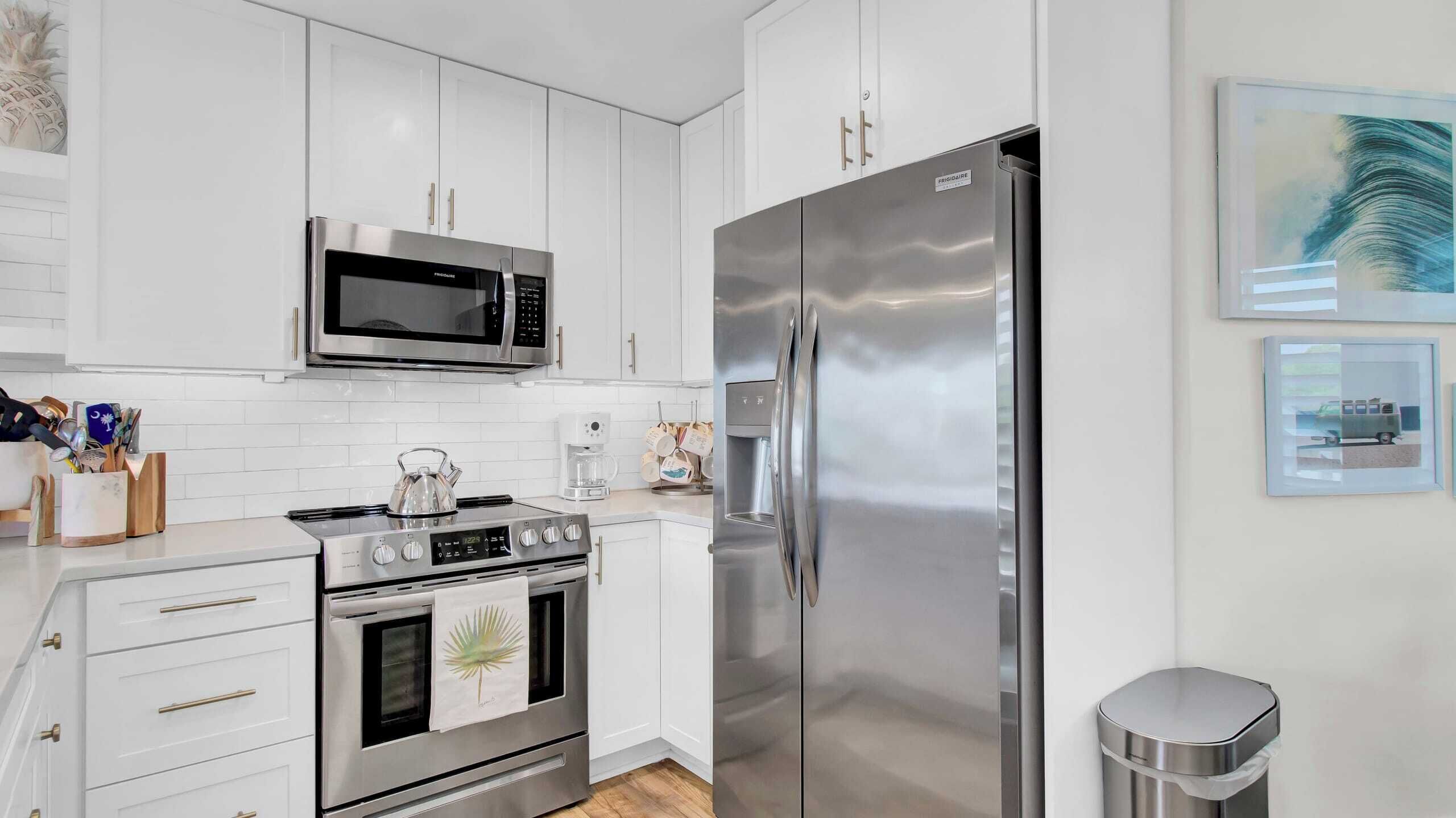 A modern kitchen with stainless steel appliances, white cabinetry, and a coffee machine.