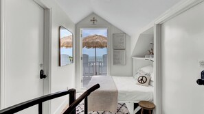 A bedroom with a bed, a small table, a chair, a balcony with a view, and a door with a lock. - 303 D Port O Call by Avantstay Oceanfront Penthouse (Isle of Palms)