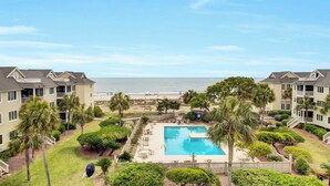A beachfront hotel with a swimming pool, palm trees, and ocean views.