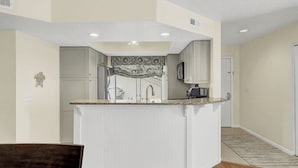 Una cocina con una isla central, muebles blancos y un salpicadero decorativo.