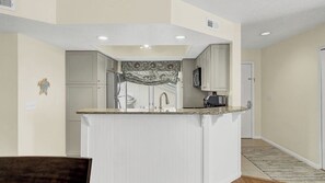 Una cocina con una isla central, muebles blancos y un salpicadero decorativo.