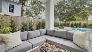 A covered outdoor seating area with a pool in the background. - 6 36th Avenue by Avantstay Stunning Private Pool (Isle of Palms)