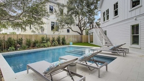 A swimming pool with lounge chairs and a wooden fence.