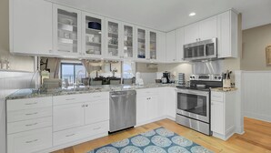 A modern kitchen with white cabinetry, stainless steel appliances, and a view to the outside.