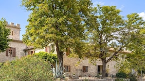 A stone building with a tower, surrounded by lush greenery and a well-maintained garden. - Gorgeous home in Carnas (Carnas)