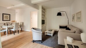 Een moderne woonkamer met een bank, een eettafel met stoelen, een salontafel en een televisie.