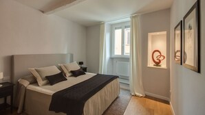 Een slaapkamer met een bed, nachtkastje, raam en kunst aan de muur.