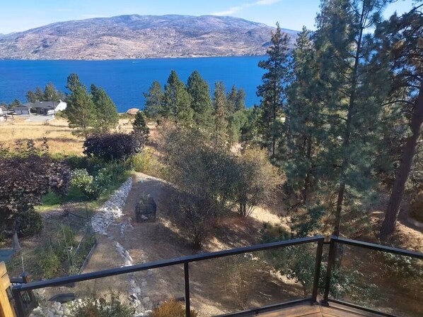 Un balcon offrant une vue sur un paysage montagneux, une étendue d’eau et une zone boisée.