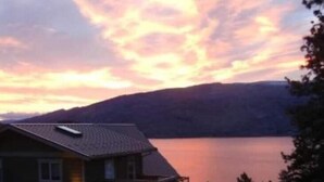 Ein Haus mit Balkon mit Blick auf einen See im Dämmerlicht.