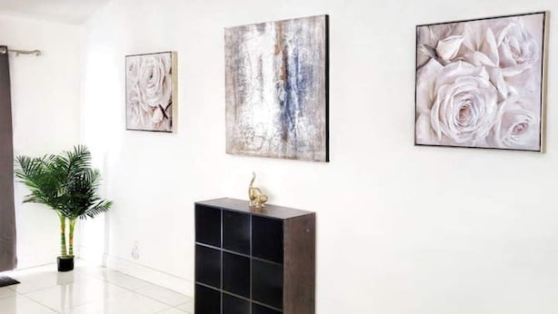 A modern interior with a black console table, a potted plant, and three framed artworks on the wall. - Panoramic Strip Views ~ Spacious, Gorgeous Home! (Las Vegas)