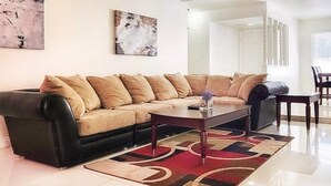 A living room with a sectional sofa, a coffee table, and a dining area with a table and chairs. - Panoramic Strip Views ~ Spacious, Gorgeous Home! (Las Vegas)