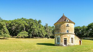 A standalone tower house with a conical roof, surrounded by a grassy field and dense trees. - Gorgeous home in CAMPSEGRET with WiFi (CAMPSEGRET)