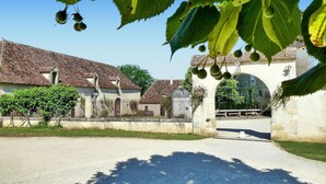 A courtyard with a stone archway, buildings with tiled roofs, and a gravel path. - Gorgeous home in CAMPSEGRET with WiFi (CAMPSEGRET)