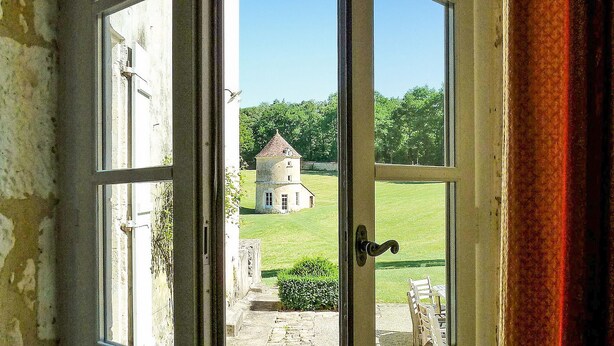 A view through a window of a building with a stone pathway leading to a tower-like structure in a grassy area. - Gorgeous home in CAMPSEGRET with WiFi (CAMPSEGRET)